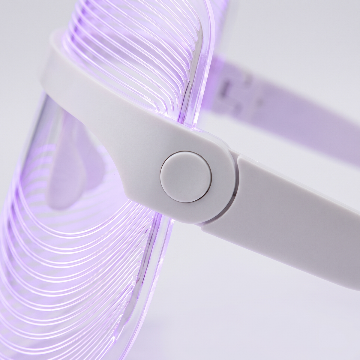 Red Light Therapy Face Mask - macro detail of control button and LED strips, purple glow